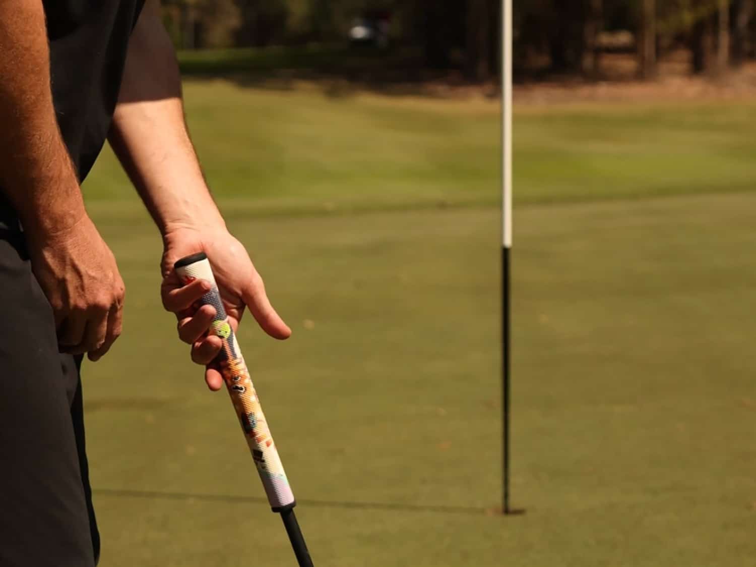A golfer uses a putter with the RipIt Monsters Ink grip.